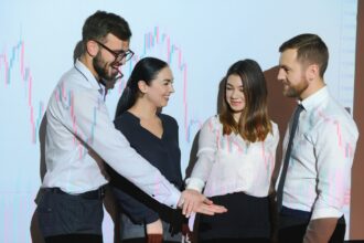 Group of business people working at modern office.Technical price graph, red and blue candlestick chart and stock trading computer screen background. Double exposure. Traders analyzing data